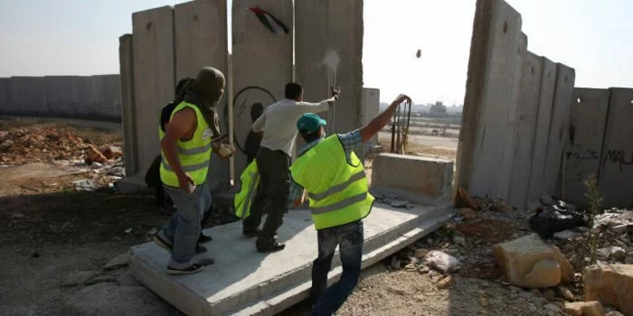 Para aktivis perdamaian lokal dan internasional berdiri di atas balok beton, bagian dari tembok pemisah Israel yang kontroversial, setelah menariknya hingga jatuh saat protes di dekat Kota Ramallah, Tepi Barat, tanggal 9 November 2009 untuk menandai peringatan 20 tahun jatuhnya Tembok Berlin di Jerman. (Foto: Getty Images/AFP/Abbas Momani)