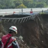 Petugas melintas di sekitar jalan tol yang amblas di ruas tol Bocimi KM 64, Sukabumi, Jawa Barat, Kamis (4/4/2