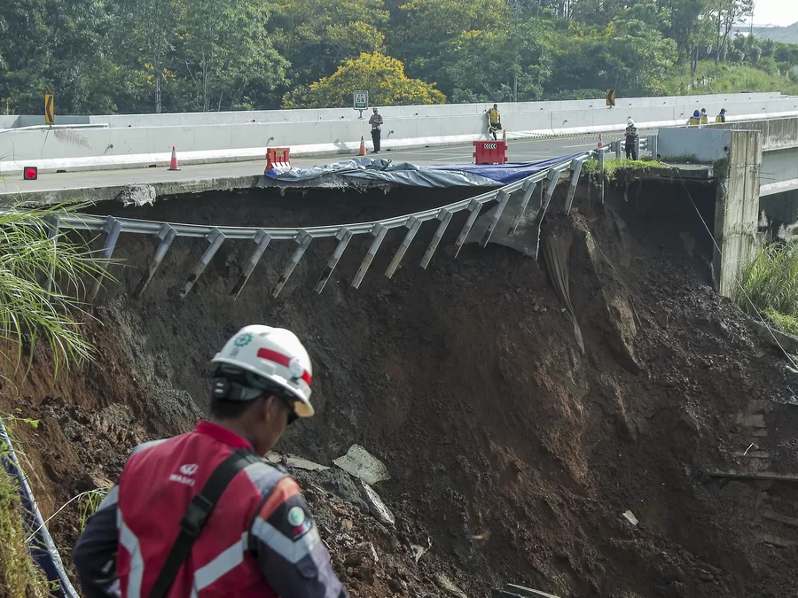 Petugas melintas di sekitar jalan tol yang amblas di ruas tol Bocimi KM 64, Sukabumi, Jawa Barat, Kamis (4/4/2