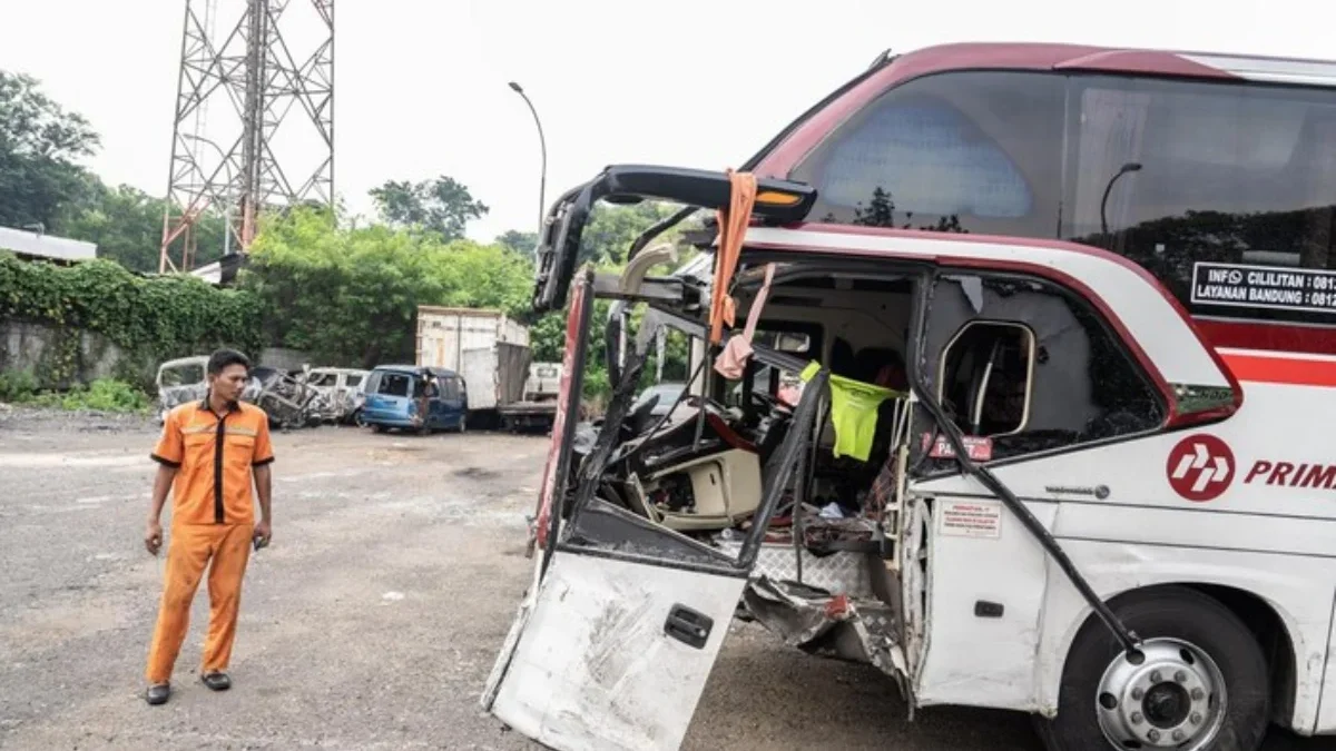 Seorang petugas melihat kondisi bus yang ringsek bagian depannya setelah terlibat kecelakaan di Tol Jakarta-Ci