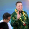 Elon Musk melambaikan tangan setelah menandatangani dokumen sebelum meresmikan unit satelit Starlink di pusat