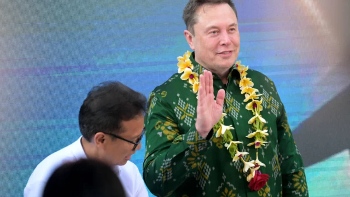 Elon Musk melambaikan tangan setelah menandatangani dokumen sebelum meresmikan unit satelit Starlink di pusat