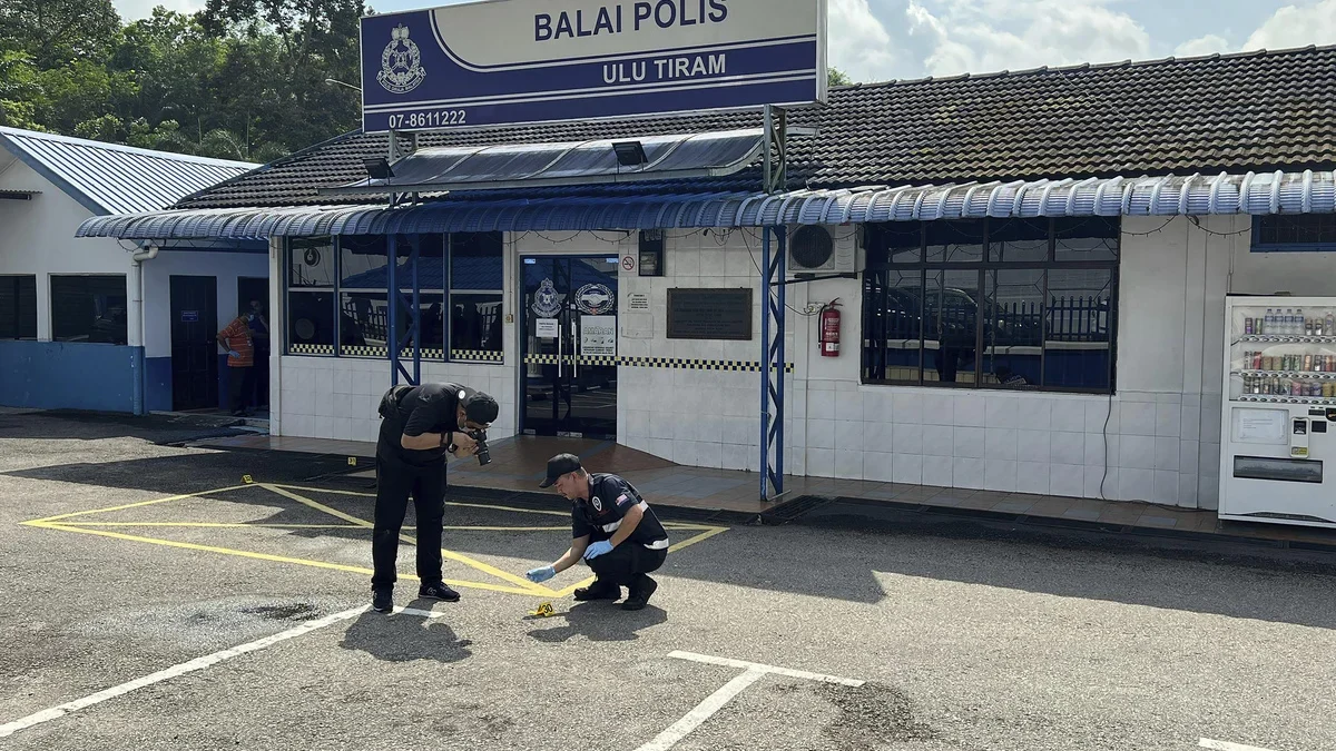 Petugas forensik kepolisian mengambil gambar di luar kantor polisi Ulu Tiram, Negara Bagian Johor, Malaysia, 1