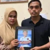 Afrinaldi (36, kanan) dan Anggun (32) berfoto dengan potret almarhum putra sulung mereka, Afif Maulana (13), d