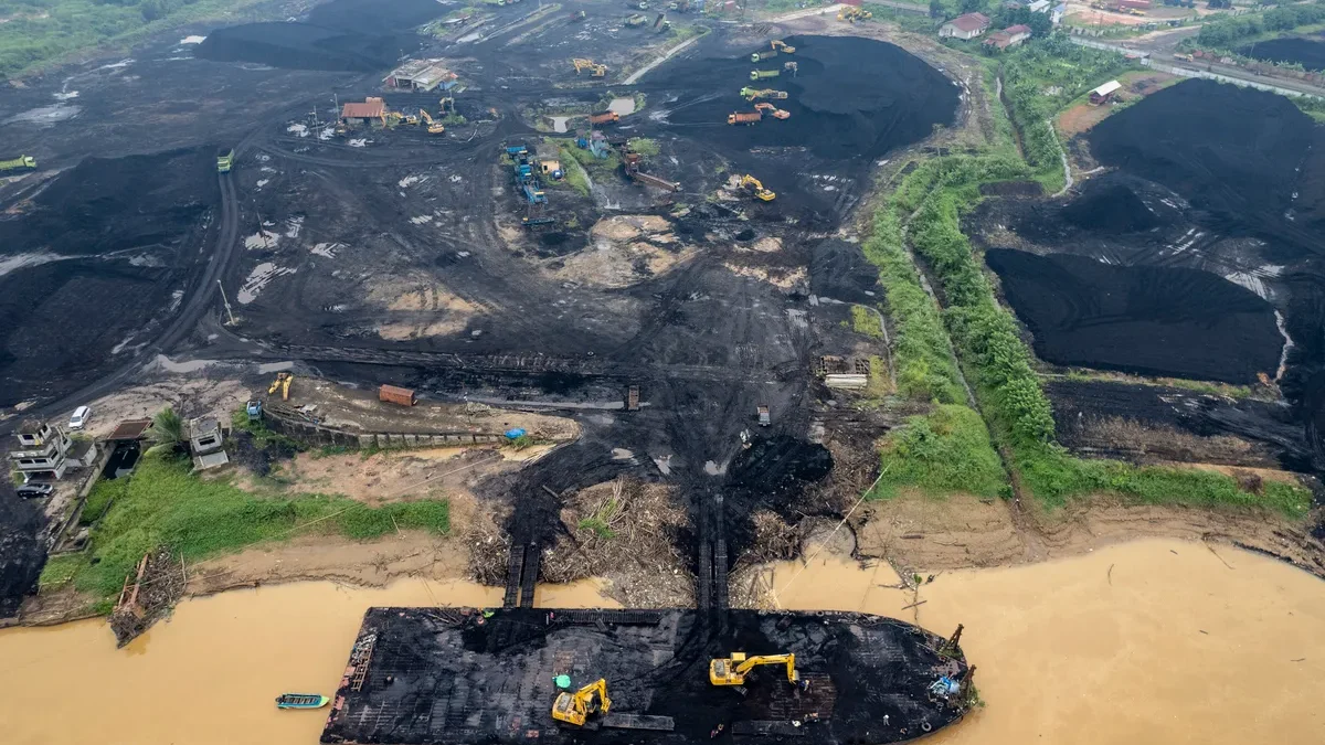 Foto udara alat berat memuat batu bara di tempat penampungan batu bara, tepi Sungai Batanghari, Muaro Jambi, J