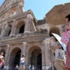 Wisatawan berlindung di bawah payung saat berkunjung ke Colosseum, Roma, Italia, pada 12 Juli 2024 di tengah g