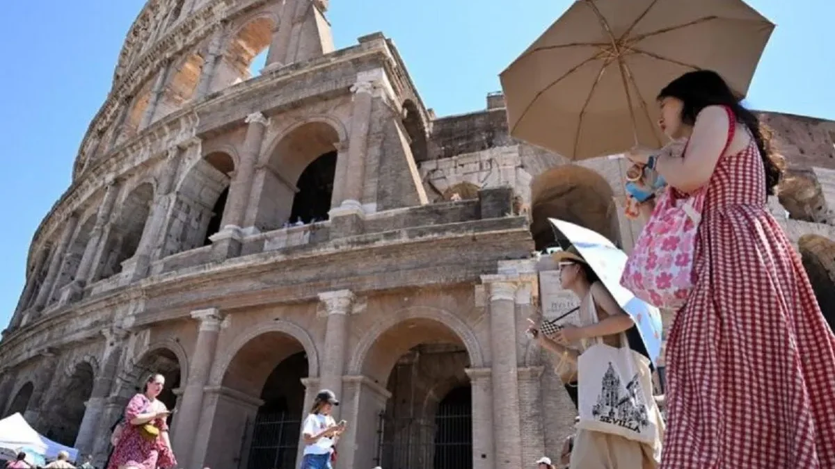 Wisatawan berlindung di bawah payung saat berkunjung ke Colosseum, Roma, Italia, pada 12 Juli 2024 di tengah g