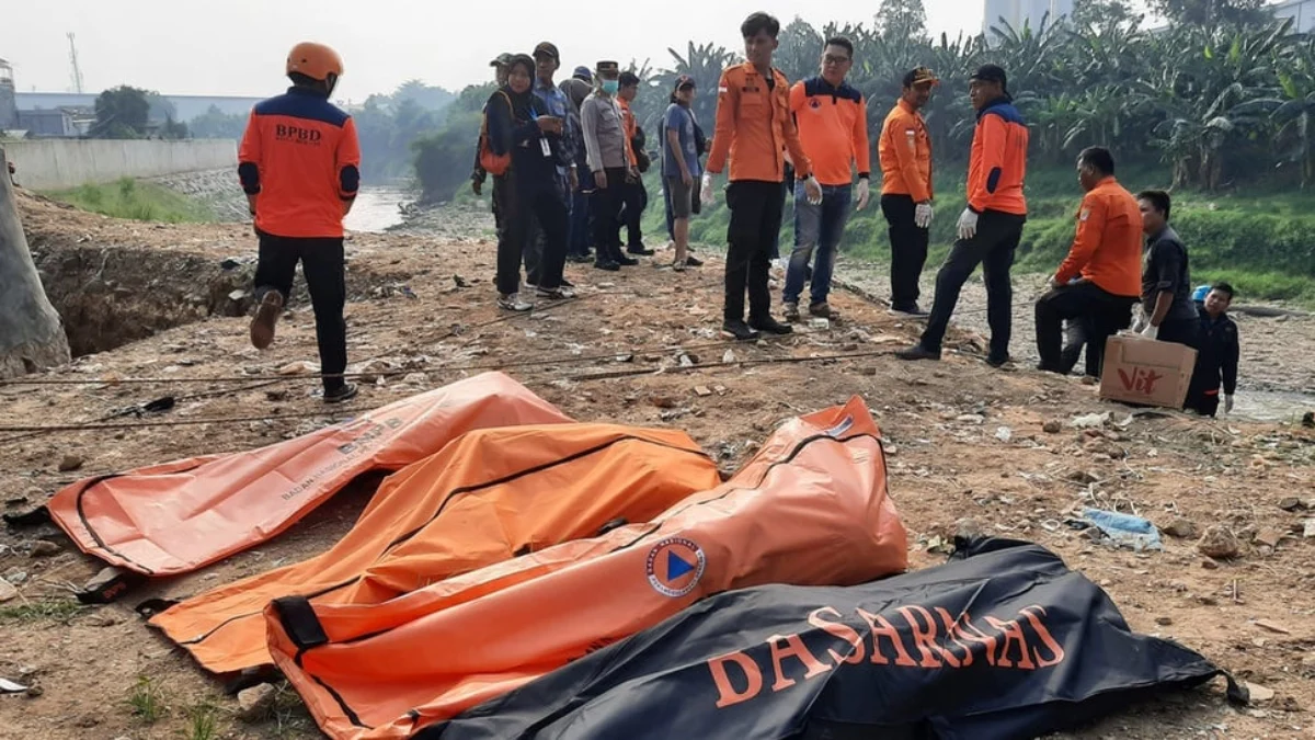 Sejumlah petugas BPBD Kota Bekasi dan polisi berdiri dengan latar depan kantong-kantong berisi tujuh jenazah l