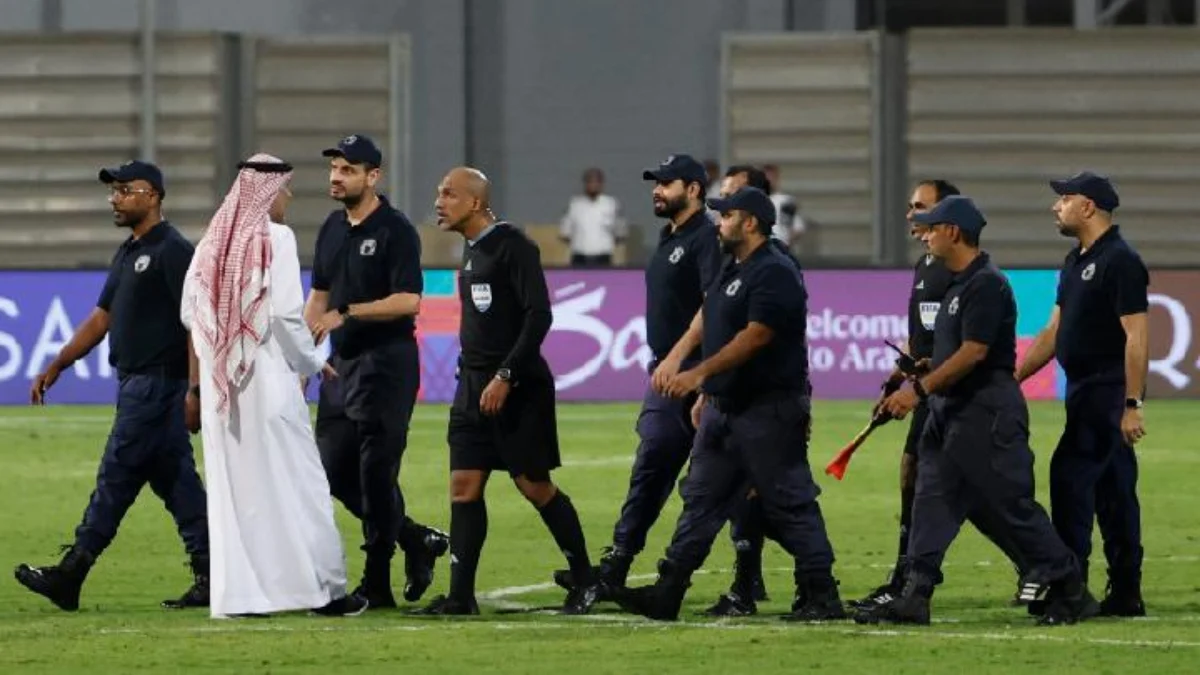 Wasit Ahmed Al-Kaf berjalan di antara barisan polisi seusai pertandingan putaran ketiga kualifikasi Piala Duni