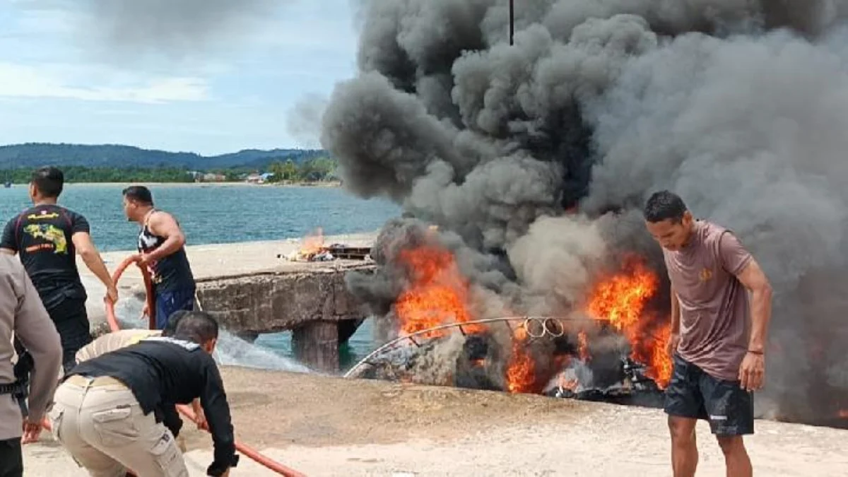 Petugas kepolisian bersama warga berusaha memadamkan api yang membakar speedboat milik Calon Gubernur Maluku U