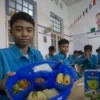 Siswa menunjukkan menu makanan bergizi gratis saat kegiatan mitigasi operasional dan uji coba makan bergizi gr