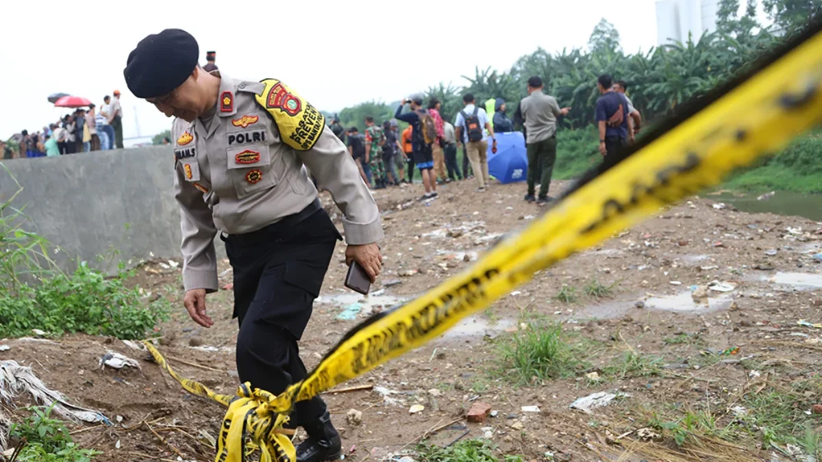 Polisi memasang garis polisi di sekitar tempat penemuan tujuh mayat di Kali Bekasi