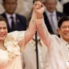 Wakil Presiden yang baru terpilih, Sara Duterte, mengangkat tangan Presiden Ferdinand Marcos Jr., saat pelanti