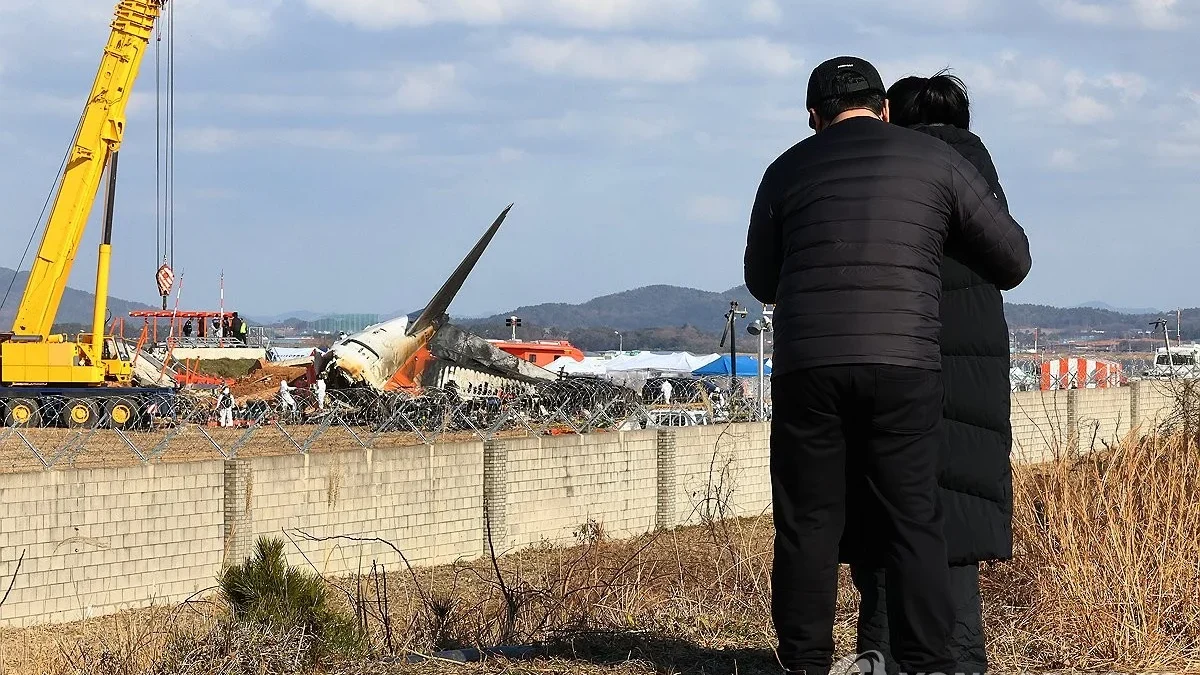 Keluarga yang berduka sedang melihat puing-puing pesawat di lokasi bencana pesawat Jeju Air di Bandara Interna