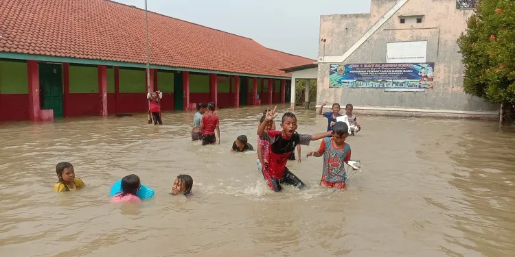 Siswa SDN 1 Bayalangu Kidul asyik main air saat banjir merendam sekolah mereka, Kamis, 16 Januari 2025.