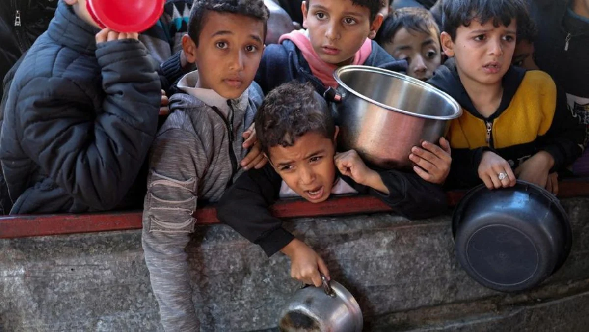 Anak-anak Palestina menunggu untuk menerima makanan yang dimasak oleh dapur amal di tengah kekurangan pasokan