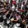 Warga Palestina menunggu untuk menerima makanan yang dimasak oleh dapur amal, di Jabalia, di Jalur Gaza utara,
