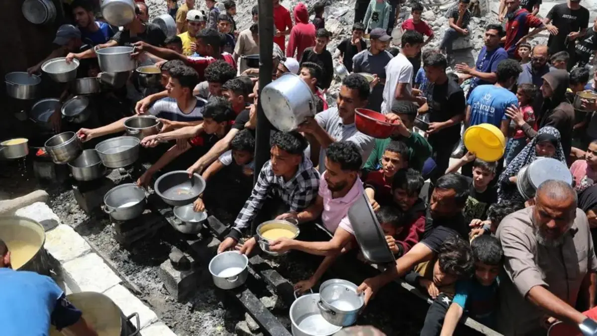 Warga Palestina menunggu untuk menerima makanan yang dimasak oleh dapur amal, di Jabalia, di Jalur Gaza utara,