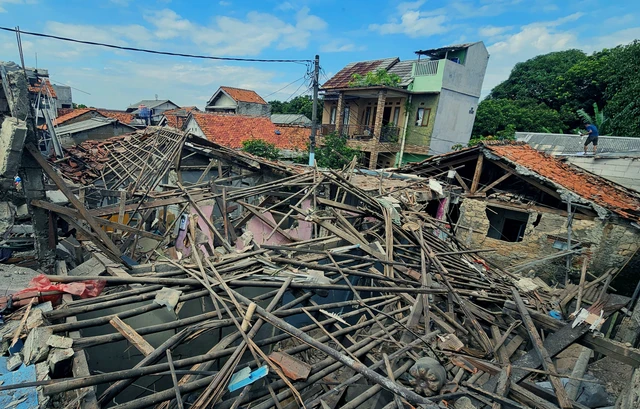 Warga berada di atas rumah yang rusak terdampak ledakan misterius di Pondok Cabe Ilir, Pamulang, Tangerang Sel