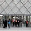 Petugas keamanan memasuki Piramida kaca Museum Louvre karena museum tetap ditutup sehari setelah perampokan pe