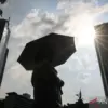 Warga menggunakan payung saat cuaca terik di kawasan Bundaran HI, Jakarta, Rabu (15/10/2025). Badan Meteorolog