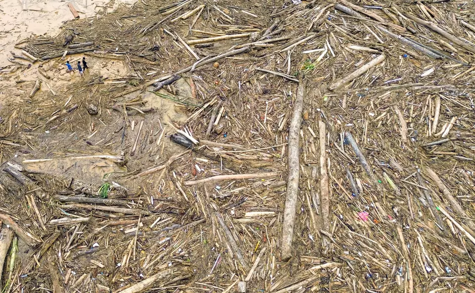 Polri Selidiki Asal Kayu Gelondongan yang Ikut Terbawa Banjir di Sumatera Foto udara sejumlah warga berjalan di antara potongan kayu gelondongan yang bertumpuk di pantai Air Tawar, Pad